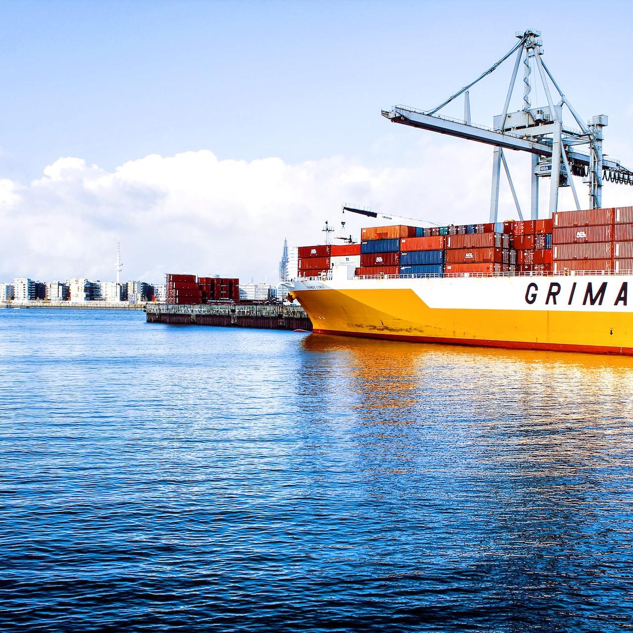 white and orange cargo ship with metal lifting equipment